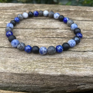 Peut inclure: Un bracelet en perles avec des pierres bleues, grises et noires. Le bracelet est fait de pierres naturelles et est un excellent accessoire pour toutes les tenues.