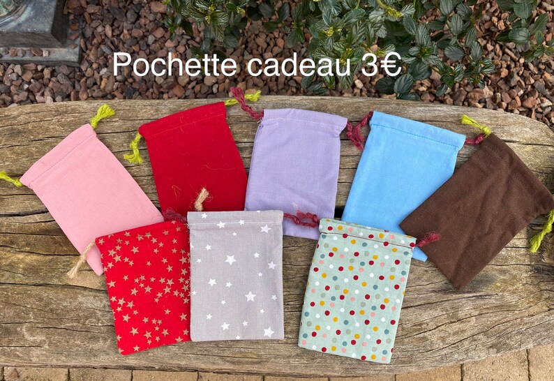 Puede incluir: Ocho peque&ntilde;as bolsas de regalo de tela con diferentes patrones y colores. Las bolsas est&aacute;n dispuestas sobre una superficie de madera. El texto "Pochette cadeau 3&euro;" es visible en la parte superior de la imagen.