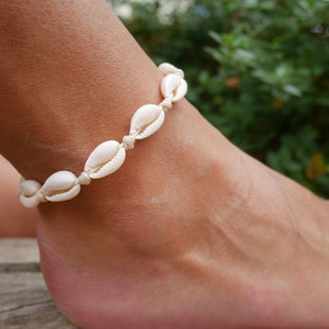 Peut inclure: Un bracelet de cheville en coquillages blancs avec un design simple. Le bracelet est composé de petites coquilles blanches enfilées sur un cordon blanc fin.