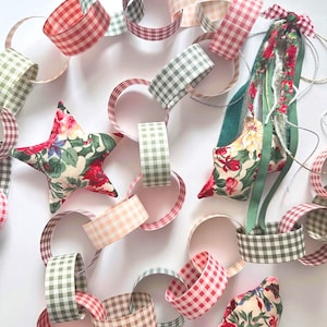 May include: A decorative paper chain garland featuring interlocking loops in various gingham patterns of red, green, pink, and brown. Interspersed among the paper links are three stuffed fabric ornaments in a floral print with red roses.