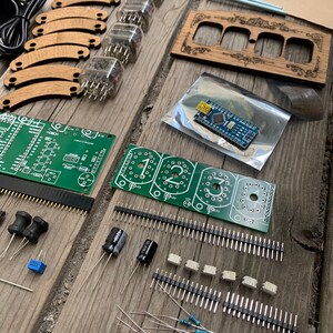 May include: An assortment of electronic components and wooden parts, including vacuum tubes, circuit boards, and resistors, arranged on a weathered wooden surface. The components are for a DIY project.