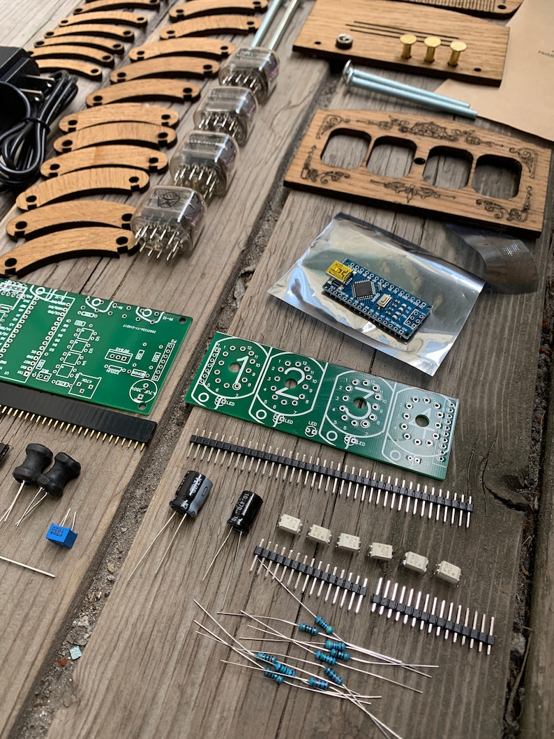 May include: An assortment of electronic components and wooden parts, including vacuum tubes, circuit boards, and resistors, arranged on a weathered wooden surface. The components are for a DIY project.