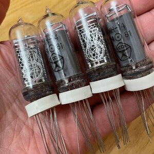 May include: Four clear glass vacuum tubes with silver metal grids and a white ceramic base. Each tube has a black label with the text "MH-14 40 81" and a red star with the text "CCCP".