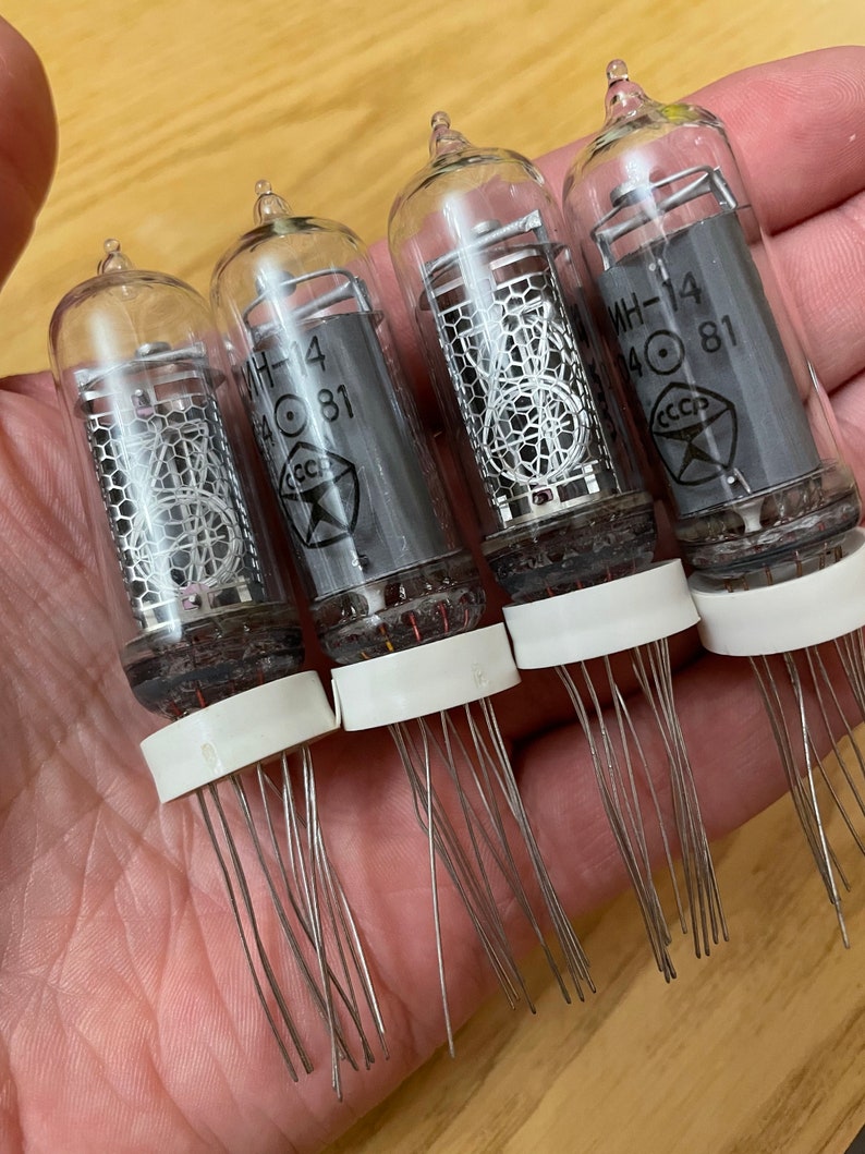 May include: Four clear glass vacuum tubes with silver metal grids and a white ceramic base. Each tube has a black label with the text "MH-14 40 81" and a red star with the text "CCCP".