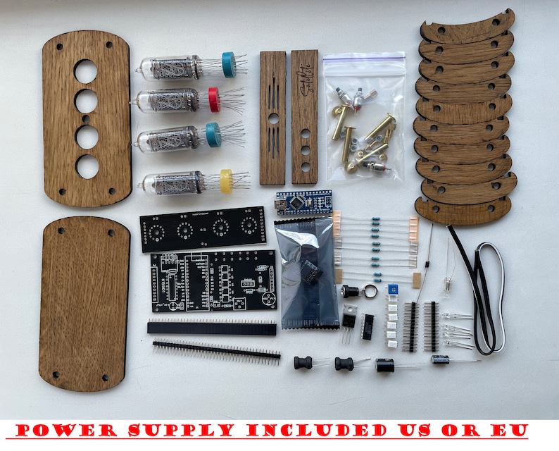 May include: A kit for building a clock using four Nixie tubes. The kit includes a printed circuit board, wooden housing, Nixie tubes, resistors, capacitors, and other electronic components. The kit also includes a power supply.