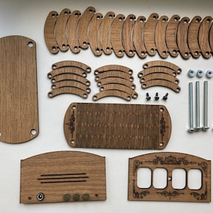 May include: A disassembled wooden craft kit with various components. The kit includes rectangular and curved wooden pieces, screws, nuts, and bolts. The wood has a natural brown color. Some pieces have decorative etched designs. The components are arranged on a white surface.