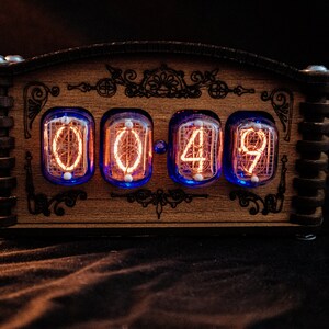 May include: A wooden digital clock displaying "00:49" with glowing orange numerals. The clock has a decorative wooden frame with ornate carvings and a dark background. The clock uses a unique retro design.
