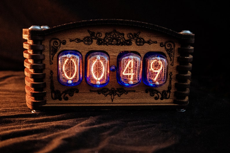 May include: A wooden digital clock displaying "00:49" with glowing orange numerals. The clock has a decorative wooden frame with ornate carvings and a dark background. The clock uses a unique retro design.