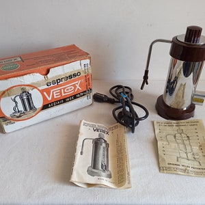 Pode incluir: Uma máquina de café expresso vintage com acabamento castanho e cromado, acompanhada pela sua caixa original e manual de instruções. A caixa apresenta a marca "VELOX" e as palavras "espresso" e "acciaio inox 18/8".