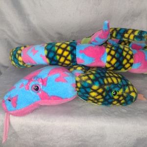 May include: A colorful plush snake toy with a pink, blue, yellow, and green patterned design. The snake has a long, segmented body and a small head with black eyes.