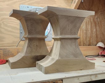 May include: Two unfinished wooden table legs. The legs are light brown, with a wide top and base, and a narrower, hourglass-shaped middle section. The legs are made of solid wood and are ready for finishing.