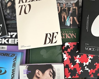 May include: A selection of K-pop albums, including a TWICE album titled "READY TO BE." Other albums feature the text "THE WORLD," "HAN SEUNG WOO," and "VICTON." The album covers are in various colours, including white, black, green, and blue.