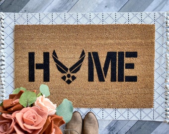 May include: A brown coir doormat with the words "HOME" in black lettering. The "O" in "HOME" is replaced with the Air Force logo.