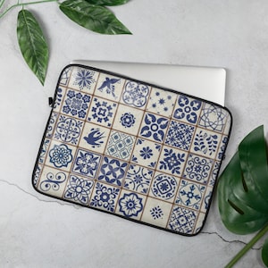 Op de afbeelding: Een laptophuls met een blauw en wit betegeld patroon. Het patroon bevat verschillende geometrische vormen en ontwerpen.