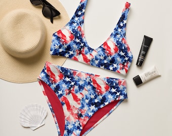 May include: A red, white, and blue swimsuit with a watercolor-style print. The swimsuit has a halter top and a high-waisted bottom.