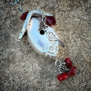 May include: A silver birdhouse charm with red glass beads and a silver bird design. The birdhouse is made from a repurposed spoon.