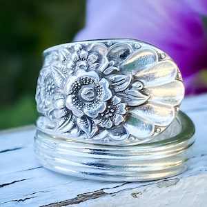 May include: A silver ring made from a vintage spoon with a floral design. The ring is made of two pieces, the top piece is a spoon with a floral design and the bottom piece is a plain band.
