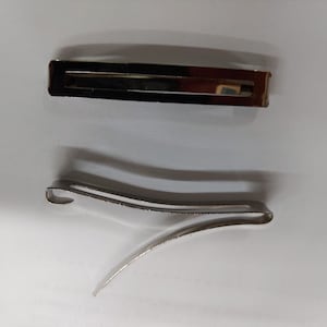 May include: Two silver hair clips, one straight and one curved.