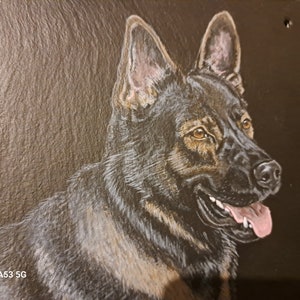 May include: A hand-painted portrait of a German Shepherd dog on a black slate background. The dog is looking to the right with its tongue sticking out. The dog's fur is black and brown.