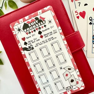 Könnte beinhalten: Eine rechteckige Spielkarte mit weißem Hintergrund und rotem Rand, die den Text SUIT YOURSELF, Spielanleitungen und ein Raster aus neun leeren Kartenumrissen enthält. Die Karte zeigt Symbole für Herz, Karo, Kreuz, Pik und Würfel.