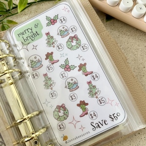 Peut inclure: Une pochette en plastique transparent contenant une feuille d'autocollants avec des illustrations sur le thème de Noël et le texte "merry & bright". La feuille d'autocollants comprend des images de sapins de Noël, de boules à neige et de bottes de cow-boy. Le texte "Save 50" est également visible.