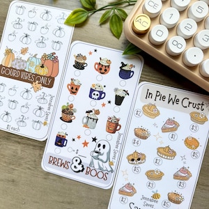 May include: Three decorative cards with fall-themed designs. One card features pumpkins and the text "Gourd Vibes Only." Another card has coffee mugs with Halloween decorations, and the third card displays pie slices. A calculator is in the background.