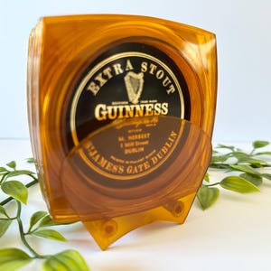 Peut inclure: Un ensemble de dessous de verre Guinness ambr&eacute;s avec le logo Guinness Extra Stout. Les dessous de verre sont dans un support de couleur ambre assortie. Le support et les dessous de verre sont en plastique transparent.