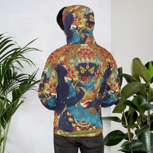 Pode incluir: Um moletom azul com um estampado colorido de uma divindade com m&uacute;ltiplos olhos e uma coroa de cr&acirc;nios. A estampa &eacute; de estilo tradicional budista tibetano.