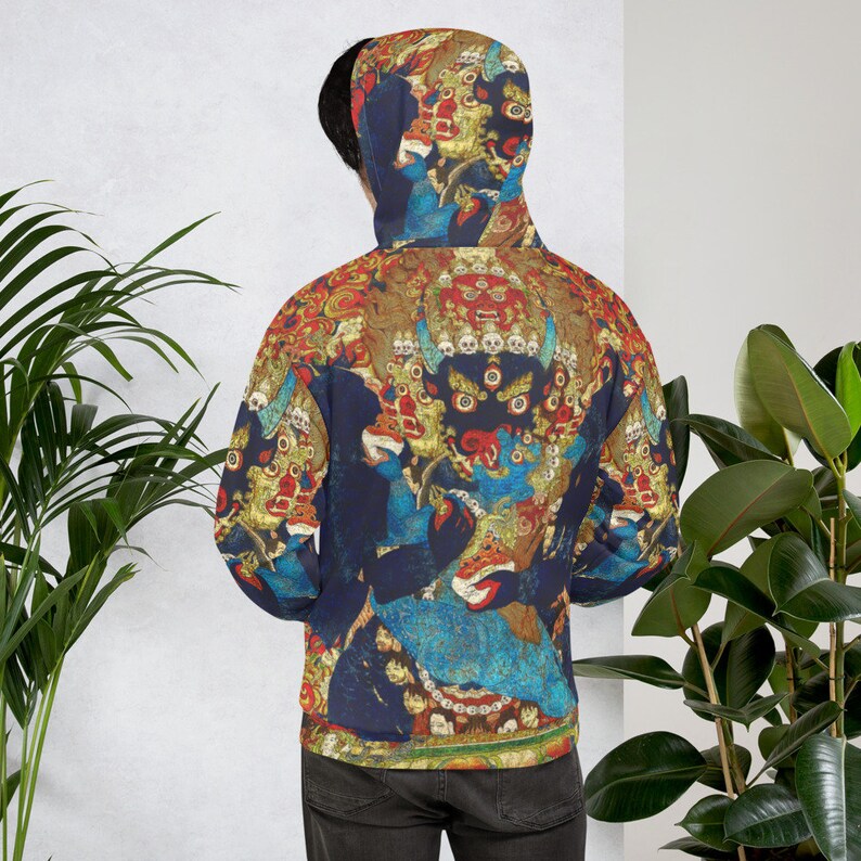 Pode incluir: Um moletom azul com um estampado colorido de uma divindade com m&uacute;ltiplos olhos e uma coroa de cr&acirc;nios. A estampa &eacute; de estilo tradicional budista tibetano.