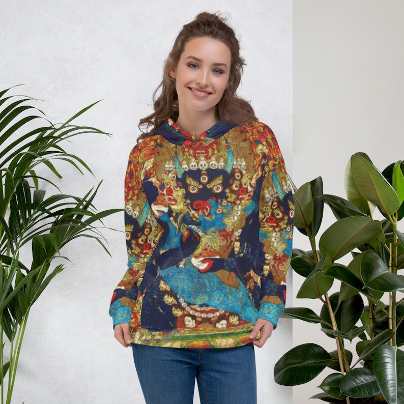 Pode incluir: Um moletom azul, vermelho e dourado com um design colorido e intrincado que apresenta uma divindade com m&uacute;ltiplos olhos e uma coroa. O moletom tem um capuz com cord&atilde;o e um bolso canguru.