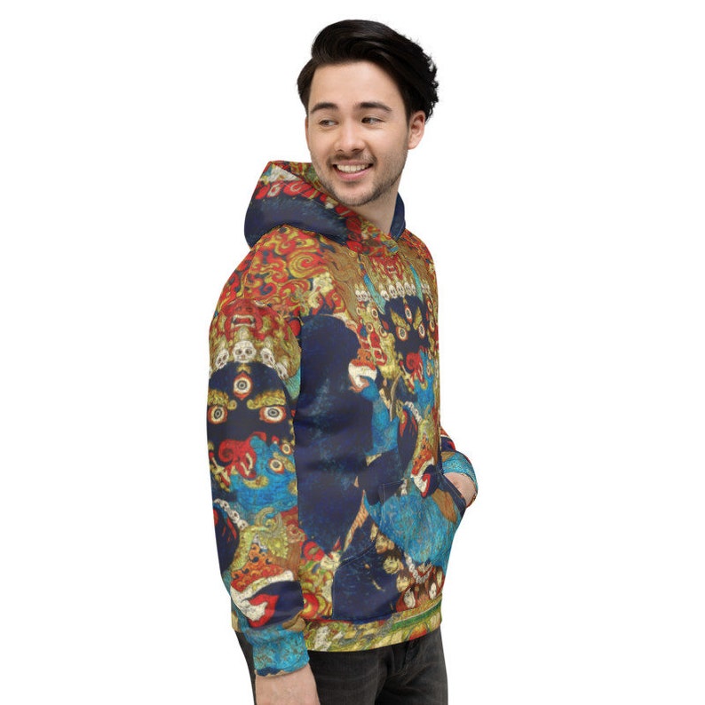Pode incluir: Um moletom azul marinho com um padr&atilde;o colorido e intrincado que apresenta uma divindade com m&uacute;ltiplos olhos e uma coroa. O padr&atilde;o &eacute; inspirado na arte tradicional tibetana.