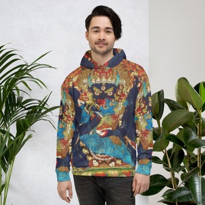 Pode incluir: Um moletom azul com um design colorido e intrincado que apresenta uma divindade com m&uacute;ltiplos olhos e uma coroa. O design &eacute; inspirado na arte tradicional tibetana.
