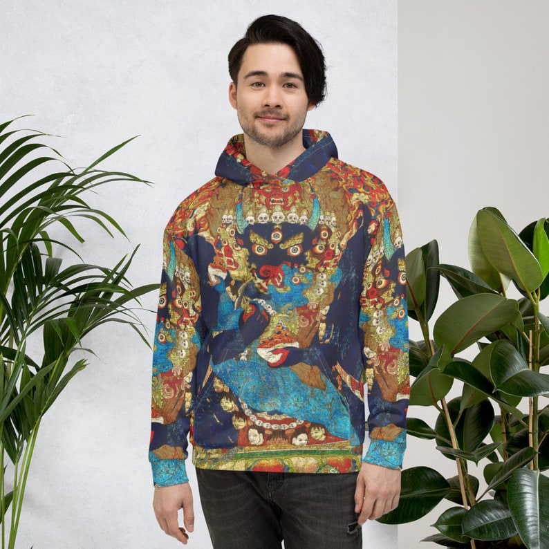 Pode incluir: Um moletom azul com um design colorido e intrincado que apresenta uma divindade com m&uacute;ltiplos olhos e uma coroa. O design &eacute; inspirado na arte tradicional tibetana.
