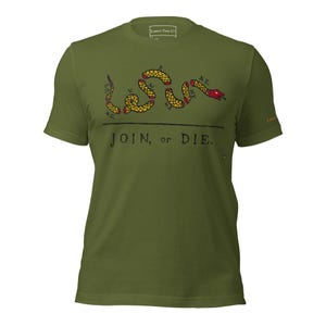 May include: An olive green t-shirt with a segmented snake design in yellow, brown, and red, and the text "JOIN, or DIE". The short-sleeved shirt has a crew neck. The design is a historical reference.