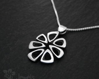 Può includere: Una collana con un ciondolo in argento a forma di fiore geometrico. Il ciondolo è realizzato in un unico pezzo di metallo e presenta un design a taglio. La collana è su una catena d'argento.