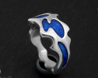 May include: A silver ring with a blue enamel design. The ring is shaped like a wave or flame.