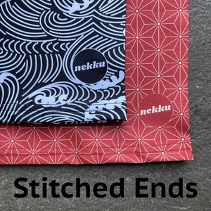 May include: Two fabric panels with stitched edges. The top panel is black with a white wave pattern and the text "nekku". The bottom panel is red with a white geometric pattern and the text "nekku".