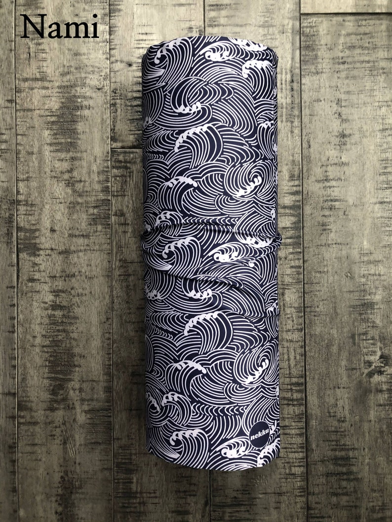 May include: A black and white patterned neck gaiter with a wave design. The gaiter is rolled up and has a small black circle with the word "nekku" printed on it.