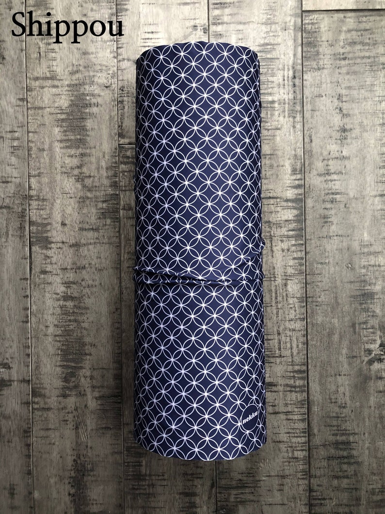 May include: A rolled up blue fabric with a white circle pattern. The fabric has the word "Shippou" printed on it and the word "nekki" printed on the bottom.