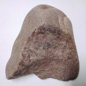 May include: A large, irregularly shaped, brown and gray rock with a smooth surface. The rock has a reddish hue in some areas.