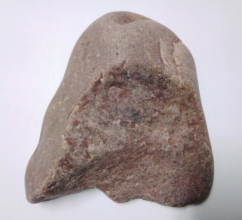 May include: A large, irregularly shaped, brown and gray rock with a smooth surface. The rock has a reddish hue in some areas.