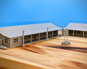 Op de afbeelding: Een 3D-geprint model van een motel met een bord waarop 'Lariat Motel' staat. Het model is gemaakt van grijs plastic en staat op een houten oppervlak.