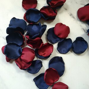 May include: A pile of navy blue and burgundy satin rose petals. The petals are arranged in a random pattern and are perfect for wedding decorations or other special events.