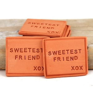 May include: A stack of terracotta tiles with the text "Sweetest Friend XO" on them.