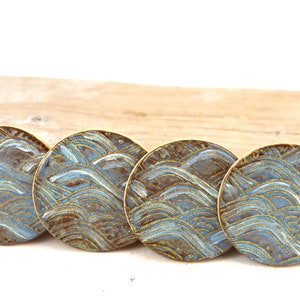 May include: Four round ceramic coasters with a blue and brown wave pattern.