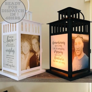 May include: Two photo lanterns, one white and one black, with a glass window. The white lantern features a quote about love, while the black lantern has a quote about remembering someone. Both lanterns have a photo inside.