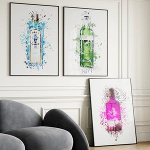 Op de afbeelding: Drie ingelijste prints van kleurrijke aquarel-achtige illustraties van gin-flessen. De flessen zijn blauw, groen en roze.