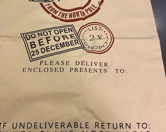 May include: A white canvas sack with red and black text and graphics. The text reads "Express Delivery from the North Pole" and "Do Not Open Before 25 December". There is a red circle with a black reindeer pulling a sleigh with a black figure in it. There is a black circle with the text "List 2x Checked". The text "Please Deliver Enclosed Presents To:" and "If Undeliverable Return To: Santa Claus, North Pole" is also printed on the sack.