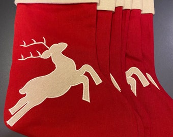 May include: Set of six red Christmas stockings with a white reindeer design. The stockings have a white cuff.