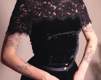 May include: A black velvet top with a lace overlay and a high neck. The top has short sleeves and a fitted silhouette.